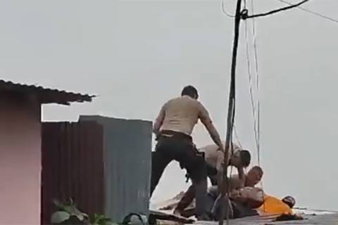Ciudadanos y policías cayeron de un techo de zinc al detener a un presunto delincuente, en Santo Domingo